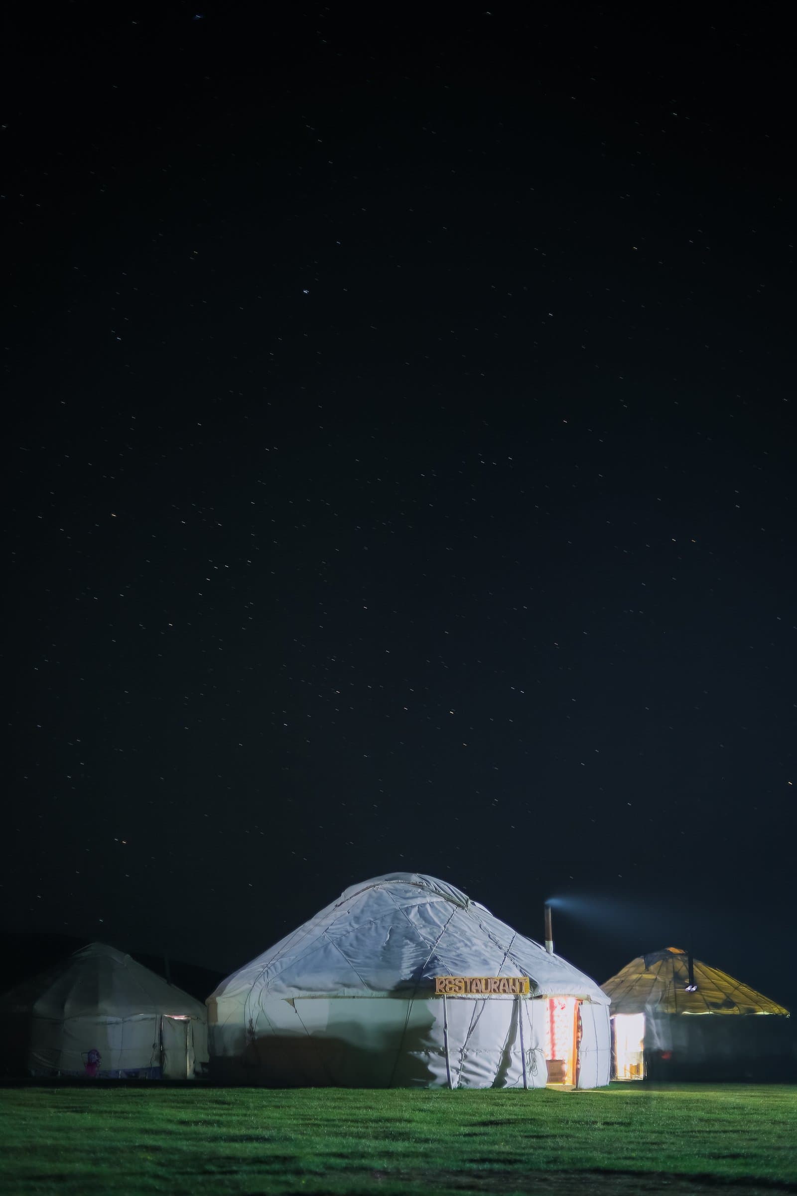 A single yurt glowing at night under a star-filled sky