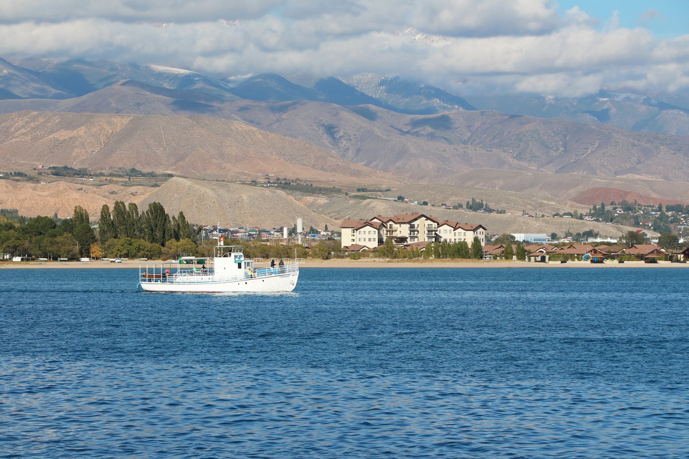 Lake Issyk-Kul with a boat on the water and mountains along the far shore