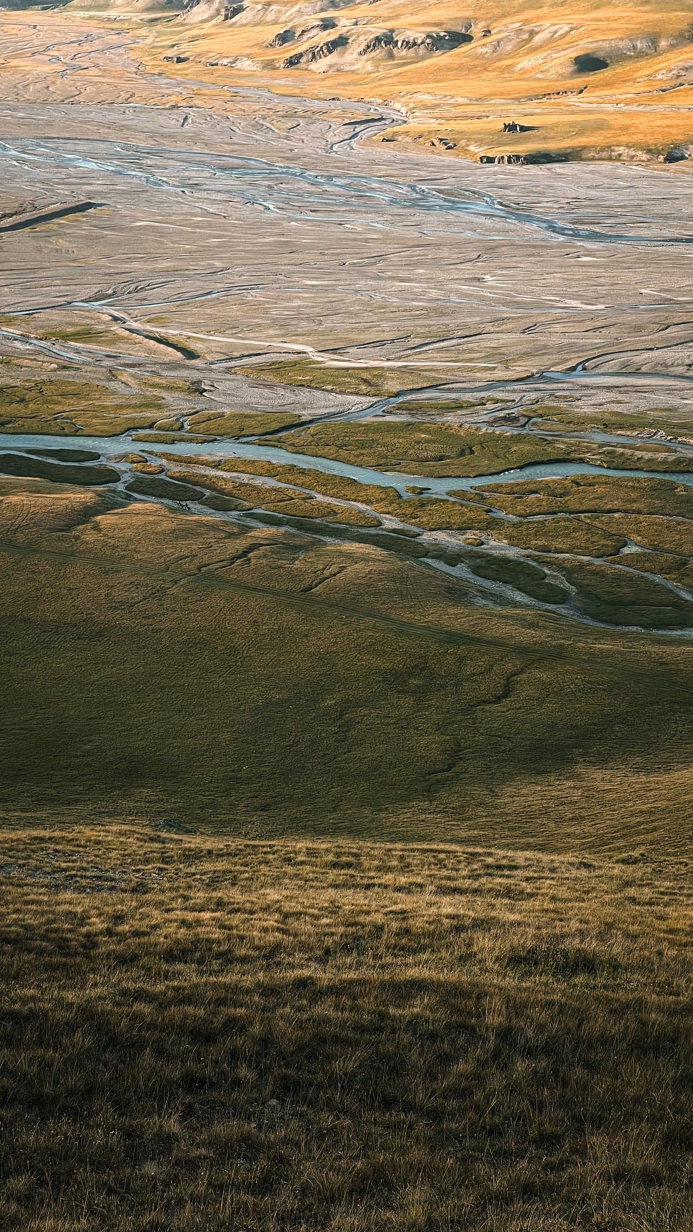 A braided river winding through the green Kilemche valley in golden light